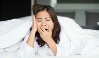 Sleepy asian woman yawning in bed at home